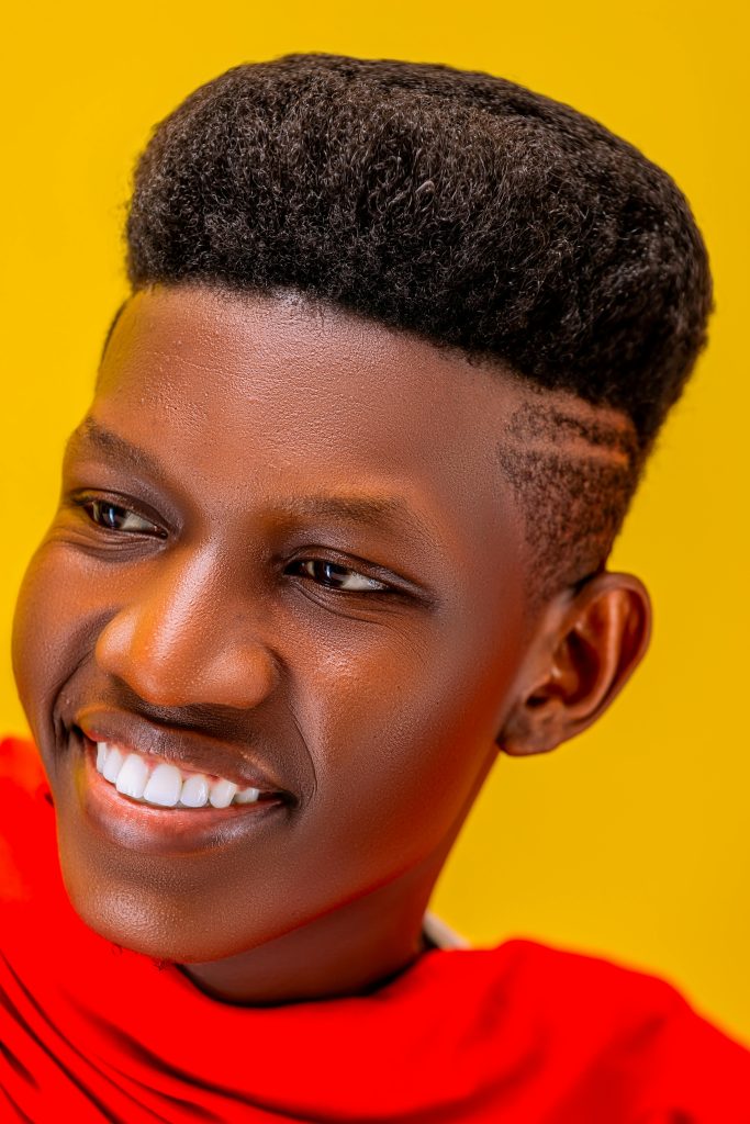 Bright portrait of a young man smiling against a vibrant yellow backdrop.