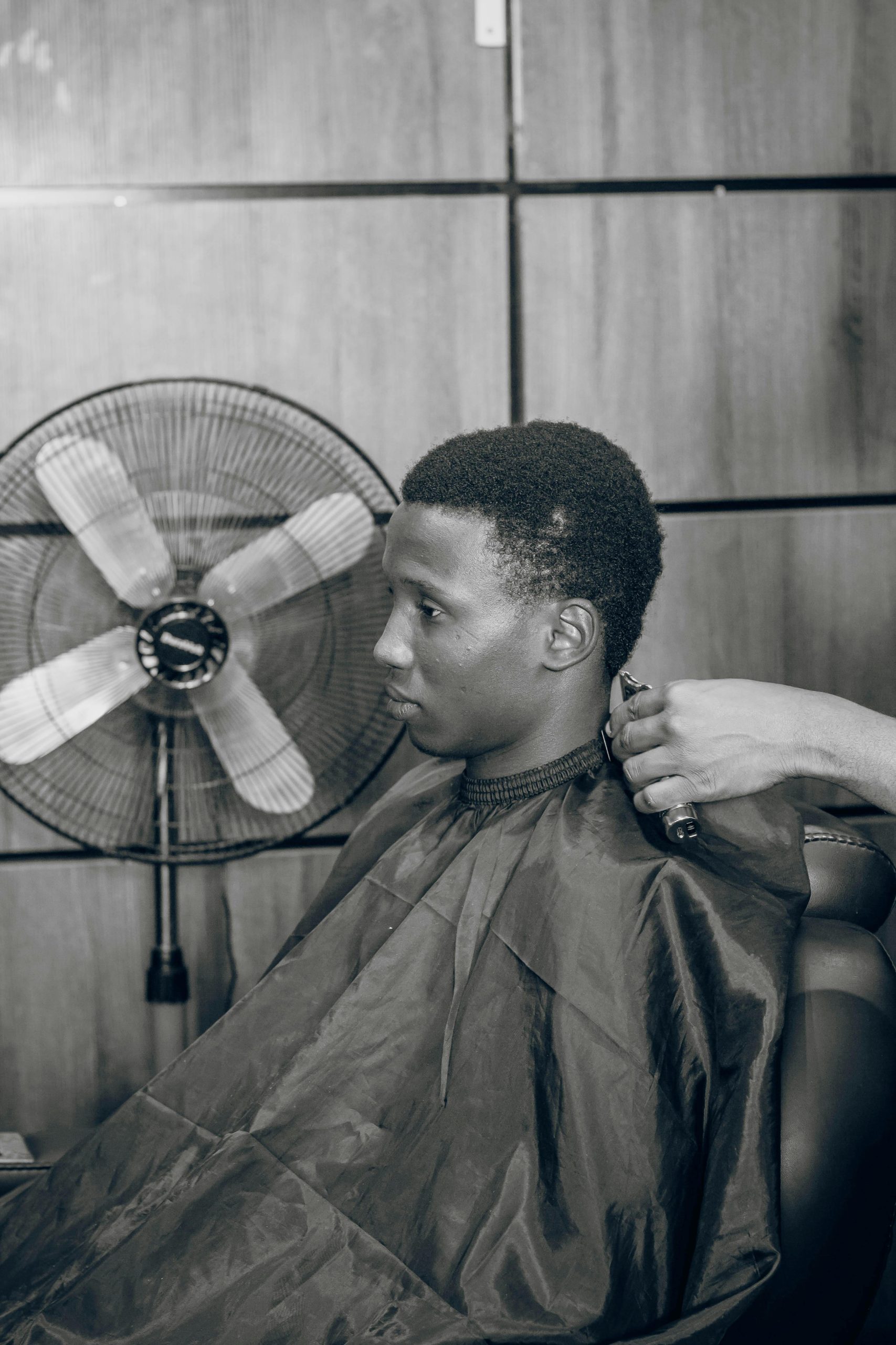 A young man in a barbershop receiving a haircut, showcasing modern grooming in a classic setting.