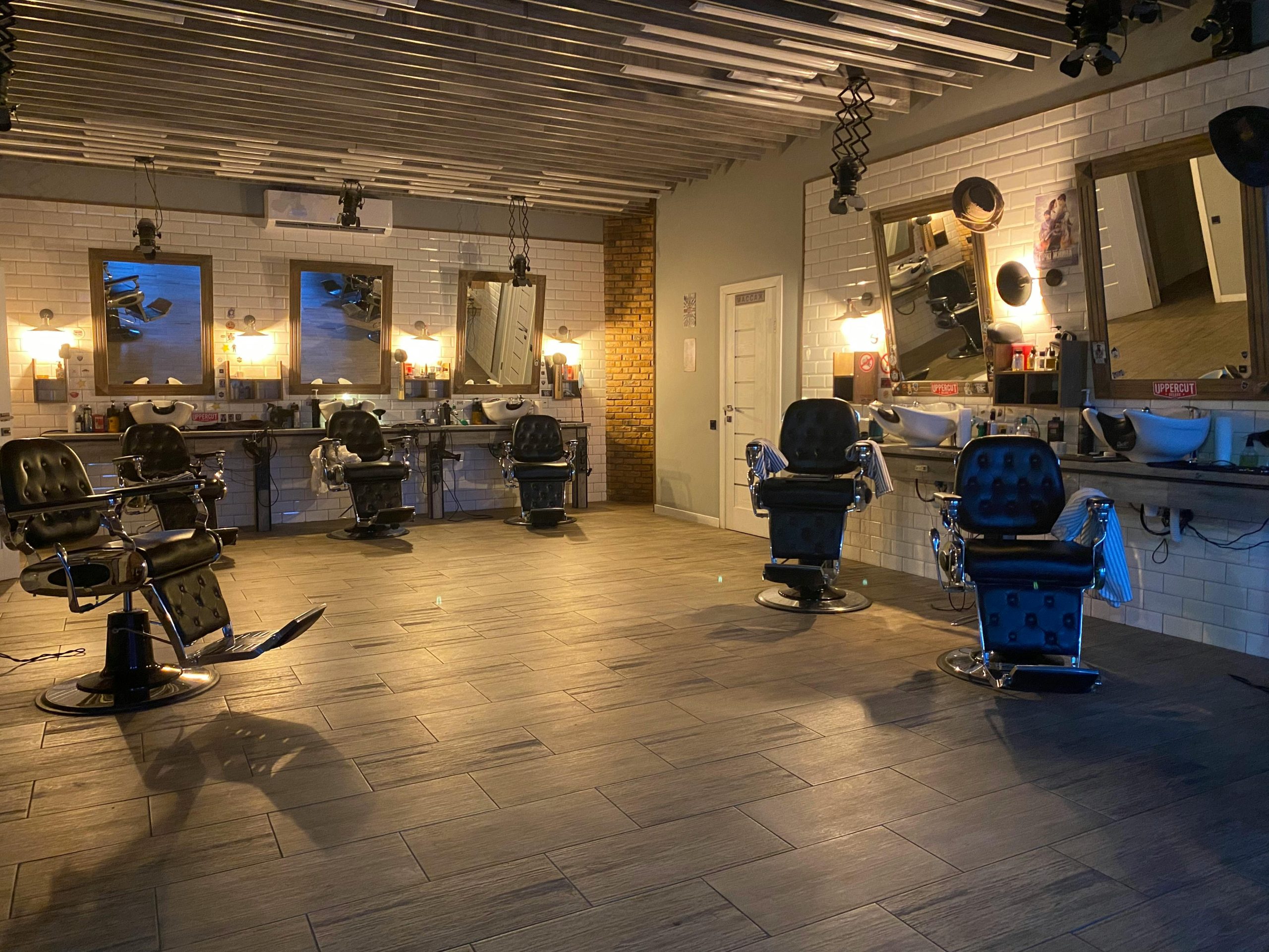 Spacious and stylish hair salon featuring empty barber chairs, mirrors, and elegant lighting.